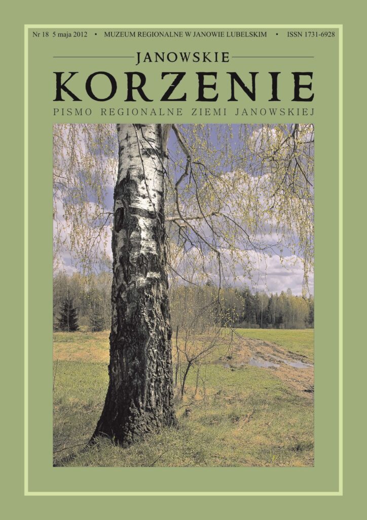 Brzoza z czarno-białą korą na tle zielonej łąki, w oddali las i niebieskie niebo z chmurami.