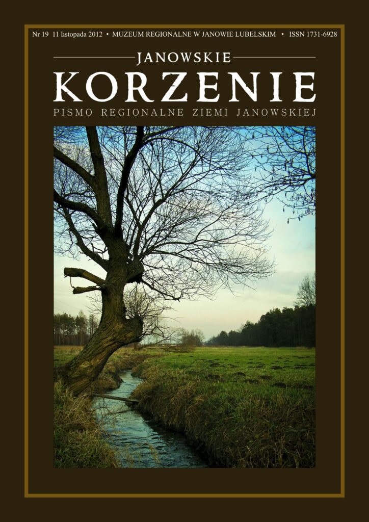 Drzewo bez liści przy strumieniu, zielone pole i las w tle pod niebieskim niebem.