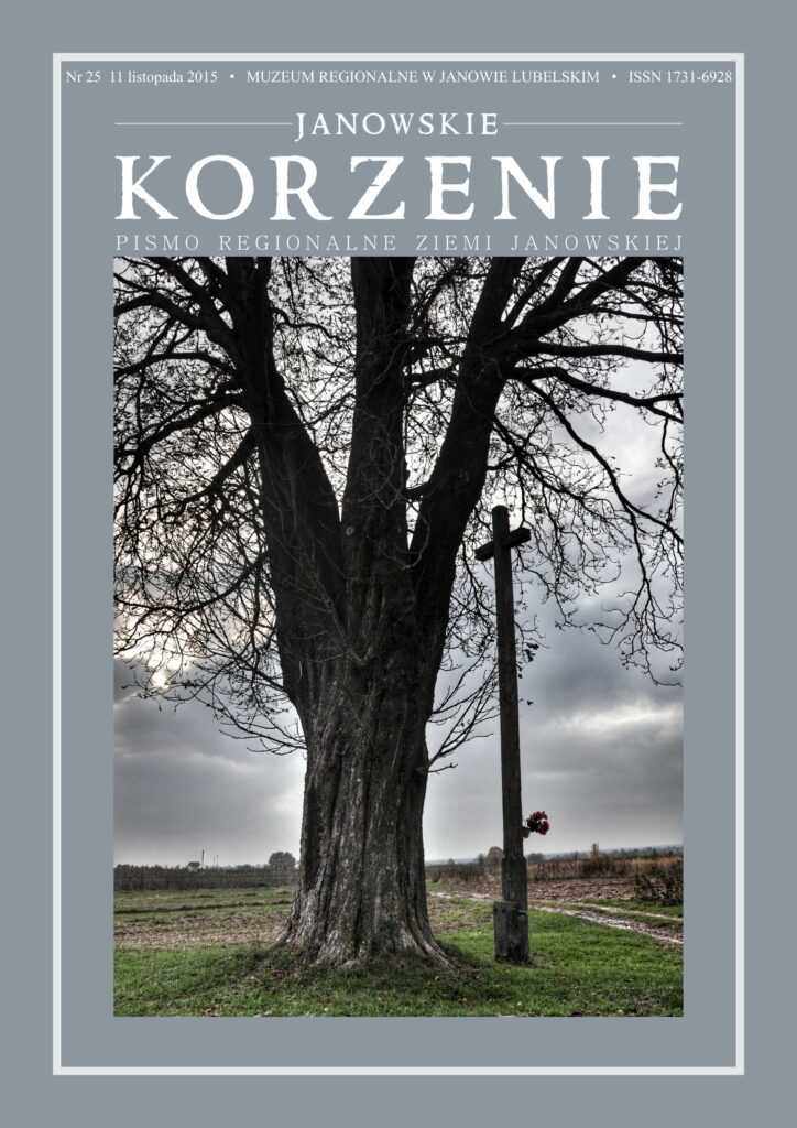 Gruby goły pień drzewa obok drewnianego krzyża z bukietem czerwonych kwiatów na tle pochmurnego nieba i pola.