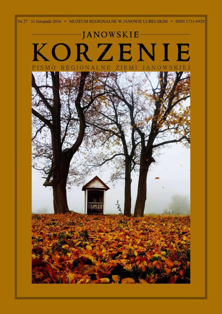 Kapliczka między drzewami z opadłymi pomarańczowo-brązowymi liśćmi na ziemi, mgła w tle.