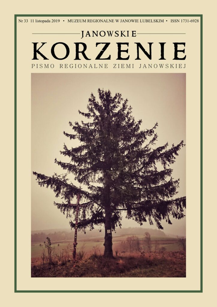 Wysokie drzewo iglaste i drewniany krzyż na tle mglistych, jesiennych pól i drzew.