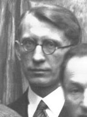 Mężczyzna w okularach owalnych, jasne włosy zaczesane do tyłu, w marynarce i krawacie, czarno-białe zdjęcie.